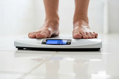 Persona mayor pesándose en una báscula digital por la mañana, clave para monitorear el balance hídrico en insuficiencia cardíaca.